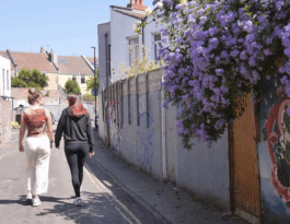 Two women walk down an alley in the daytime